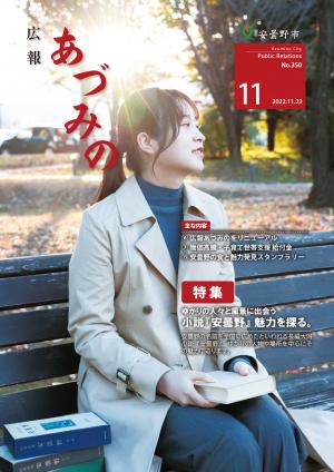 広報あづみの350号表紙 外のベンチで遠くを眺める女性がいます。手には小説「安曇野」を持っています。