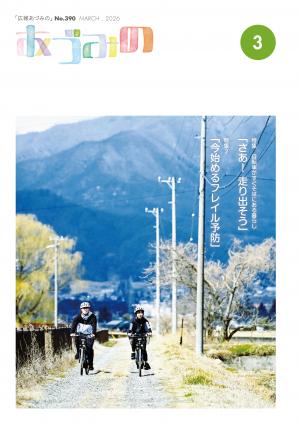 広報あづみの390号 表紙山を背景に未舗装道路を自転車で走る若い男女